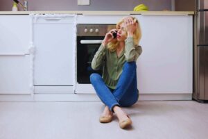 Donna seduta per terra che chiama tecnico lavastoviglie