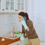 Donna che chiama l'idraulico mentre cerca di sturare il lavandino