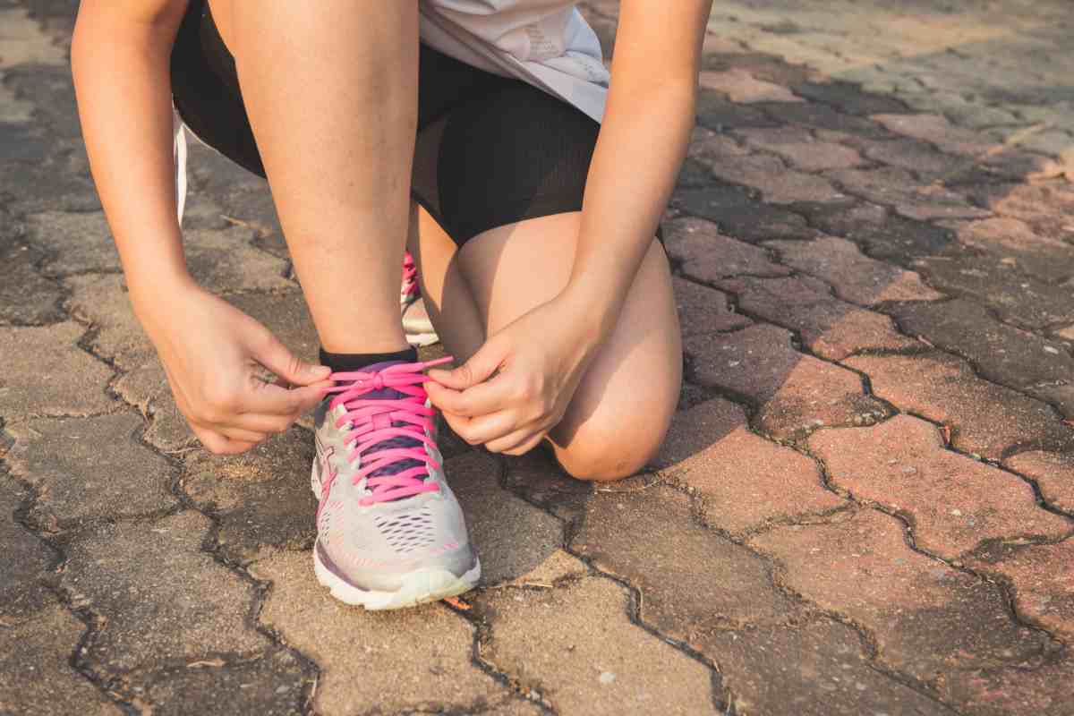 Donna in pantaloncini che si allaccia le scarpe da ginnastica