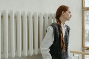 Una ragazza appoggiata a un vecchio termosifone