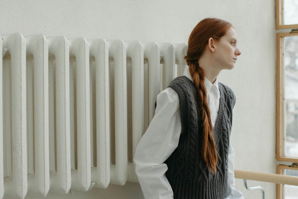 Una ragazza appoggiata a un vecchio termosifone